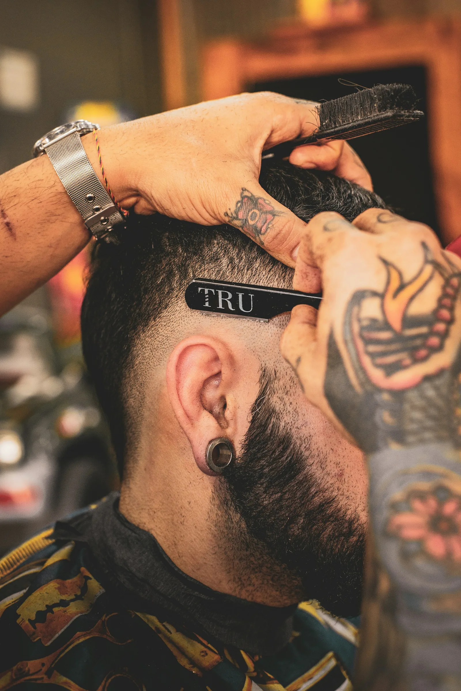 A barber carefully shaping a haircut with a straight razor — stock photography for this design concept